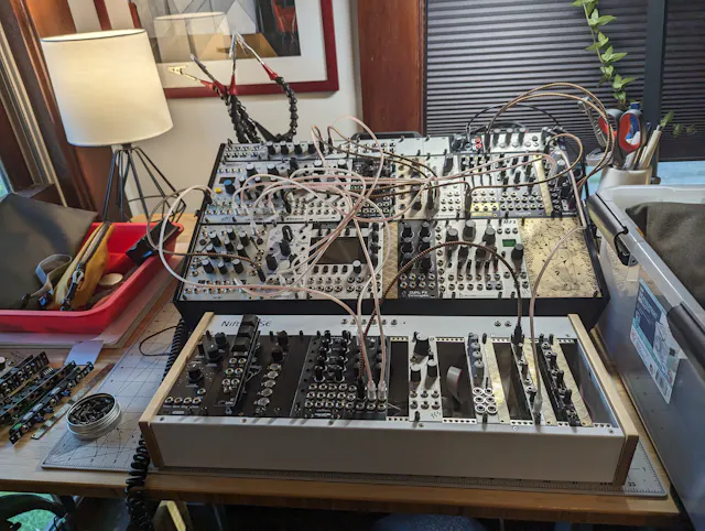 Large modular synthesizer setup with rows of modules and many patch cables on a desk.