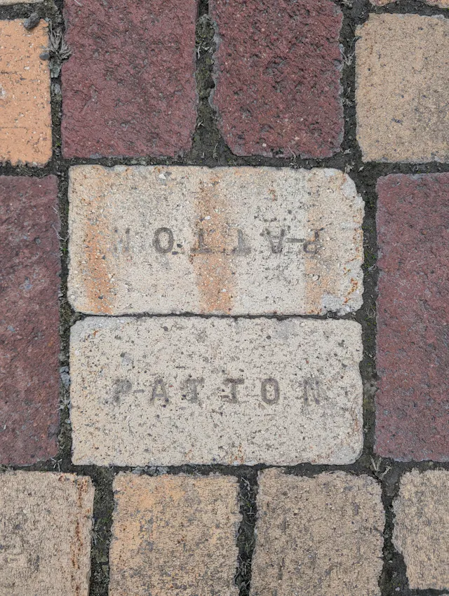 Close-up of vintage brickwork with two white stone bricks engraved with text and numbers among red clay bricks.
