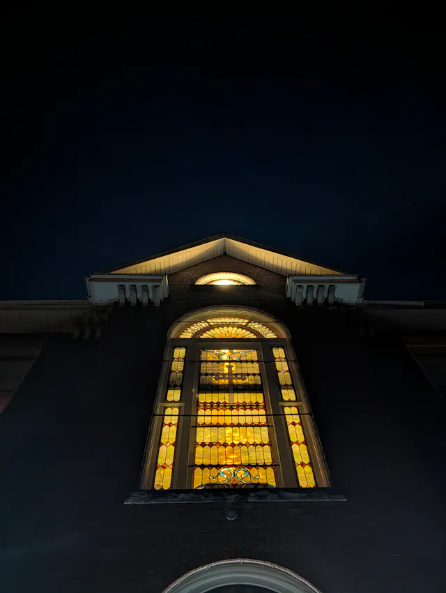 Illuminated wooden gable roof of a building photographed at night against a dark sky.