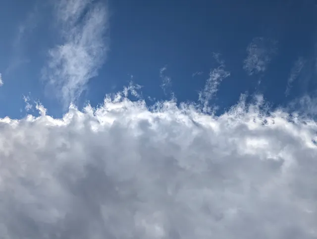 Bright blue sky with wispy white clouds layered across the frame.
