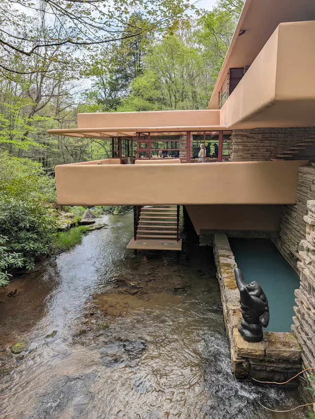 Side view of Fallingwater showing its terraces cantilevered over Bear Run, with the suspended stairs descending to the water