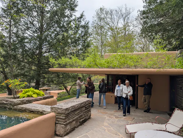 Visitors standing on Fallingwater's flagstone terrace near the plunge pool, beneath the cantilevered roof