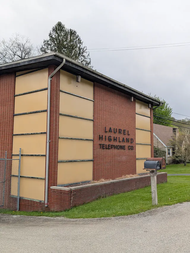 The brick side of the Laurel Highland Telephone Co. building, with cream-colored panels and a mailbox at the curb